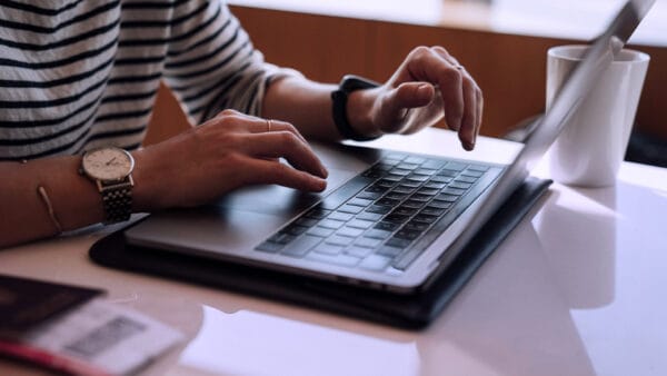 Inzoomad bild med person med randig tröja som skriver på en laptops tangentbord